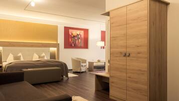 Een moderne hotelkamer met een groot bed, een houten garderobe, een bureau en een stoel.