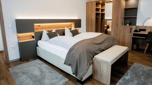 A modern bedroom with a bed, bedside tables, a desk, and a wardrobe. - Hotel Gasthof Koch (Daaden)