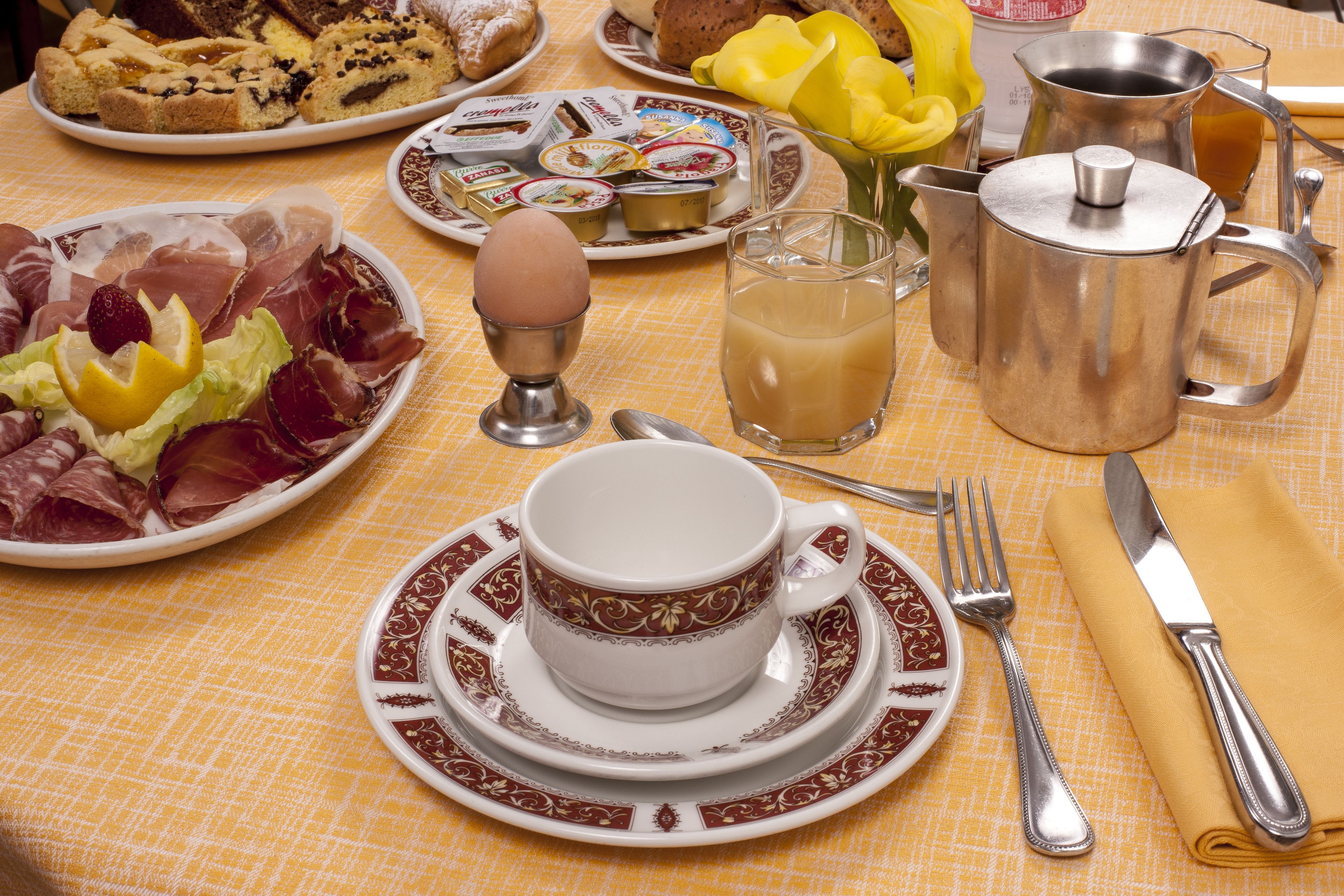 Estrat de taula per esmorzar amb plats de menjar, una cafetera i els utensilis de cuina.