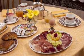 A breakfast table with plates of food, a coffee pot, a pitcher, and a glass of juice. - Hotel Brig (Cattolica)