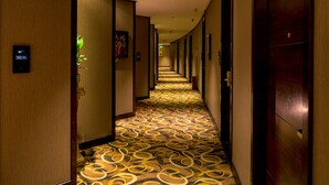 Un couloir d’hôtel avec un tapis à motifs, des portes en bois et un panneau indiquant le numéro de chambre 3036.