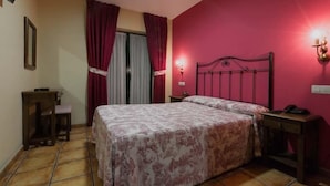 A bedroom with a bed, a nightstand, a desk, and a chair. - Apartamentos Villa de Cabrales (Cabrales)