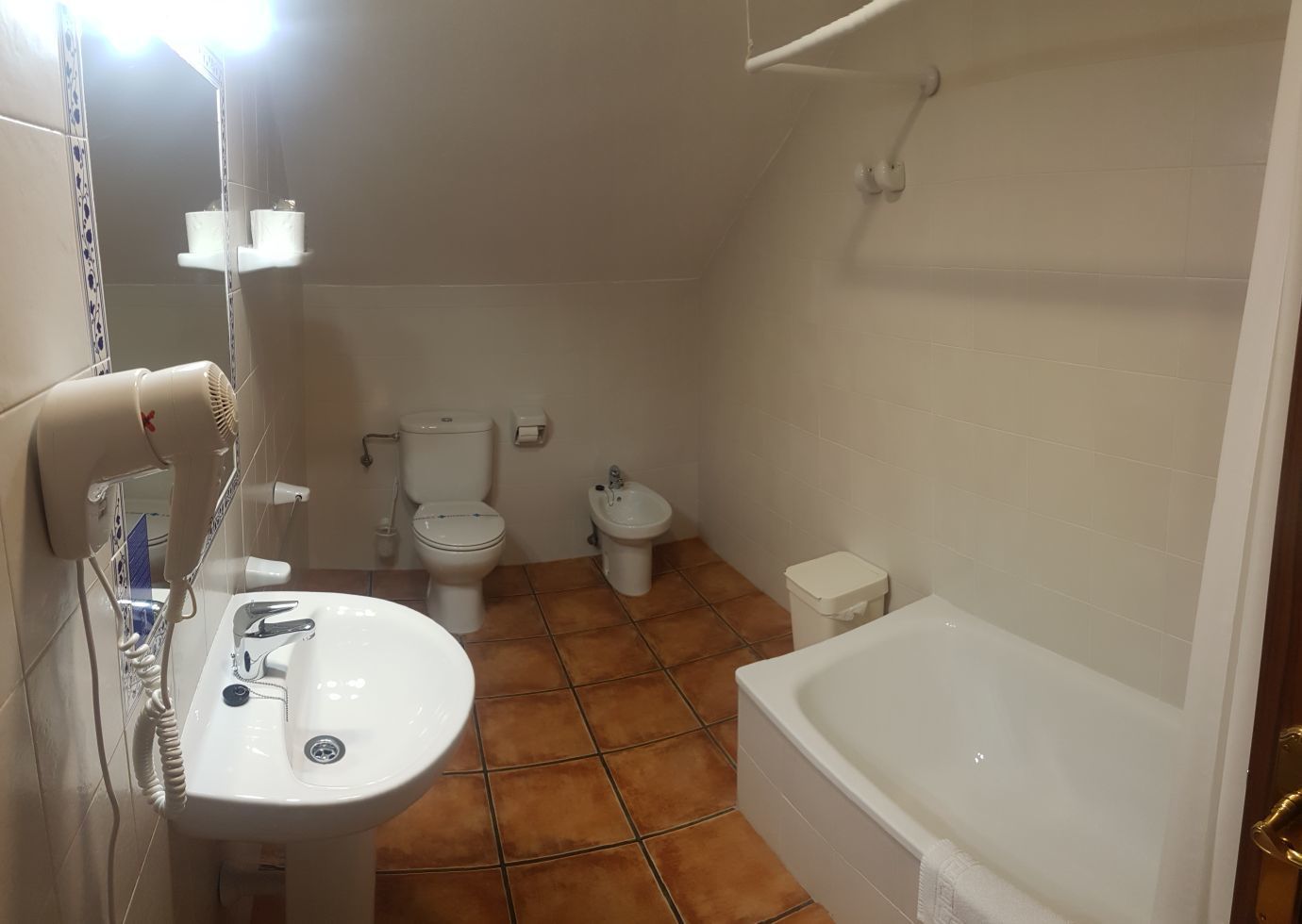 A bathroom with a sink, toilet, bidet, and bathtub.