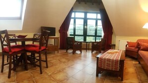 A cozy room with a dining table, chairs, a sofa, and a window with curtains. - Apartamentos Villa de Cabrales (Cabrales)
