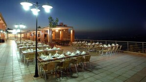 A rooftop dining area with tables and chairs, outdoor lighting, and a view of the city at night. - Safir Bhamdoun Hotel (Bhamdoun)