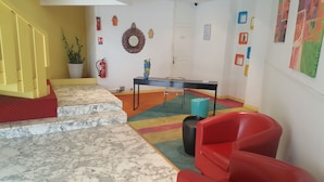 Een vrolijk ingericht interieur met een trap, een tafel, stoelen en decoratieve wandkunst.