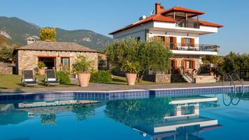 A two-story house with a swimming pool in front.