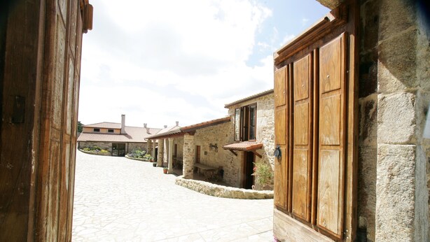 A stone pathway leading to a rustic building with wooden doors and a stone facade. - Casa da Botica (A Estrada)