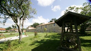 A stone building with a wooden structure in the foreground. - Casa da Botica (A Estrada)