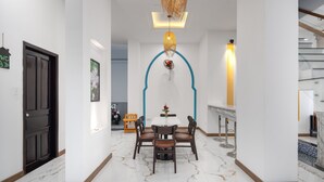 A modern dining area with a marble floor, a white table, and brown chairs. - Phuong Dong Hotel & Apartment (Quy Nhon Nam)