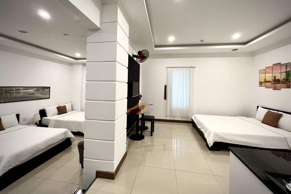 A hotel room with two beds, a desk, a chair, and a TV.