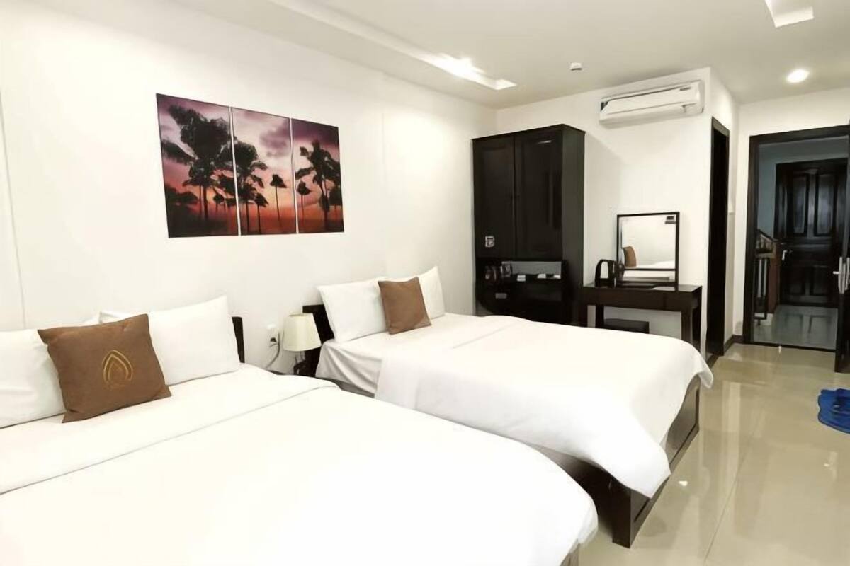 A hotel room with two beds, a desk, a chair, a mirror, and a painting on the wall.