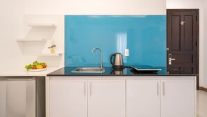 A kitchen with a blue backsplash, stainless steel sink, and a kettle. - Phuong Dong Hotel & Apartment (Quy Nhon Nam)