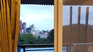 A balcony with a view of a cityscape, a sliding glass door, and a yellow curtain. - Especially Chef's Home B&B (Hualien City)