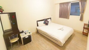 Une chambre à coucher avec un lit, un bureau, une chaise, un miroir et une fenêtre avec des rideaux.