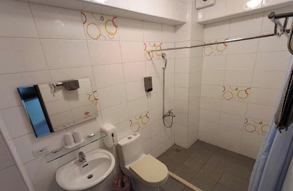 Et badeværelse med toilet, vask og bruseområde.