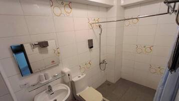 Et badeværelse med toilet, vask og bruseområde.
