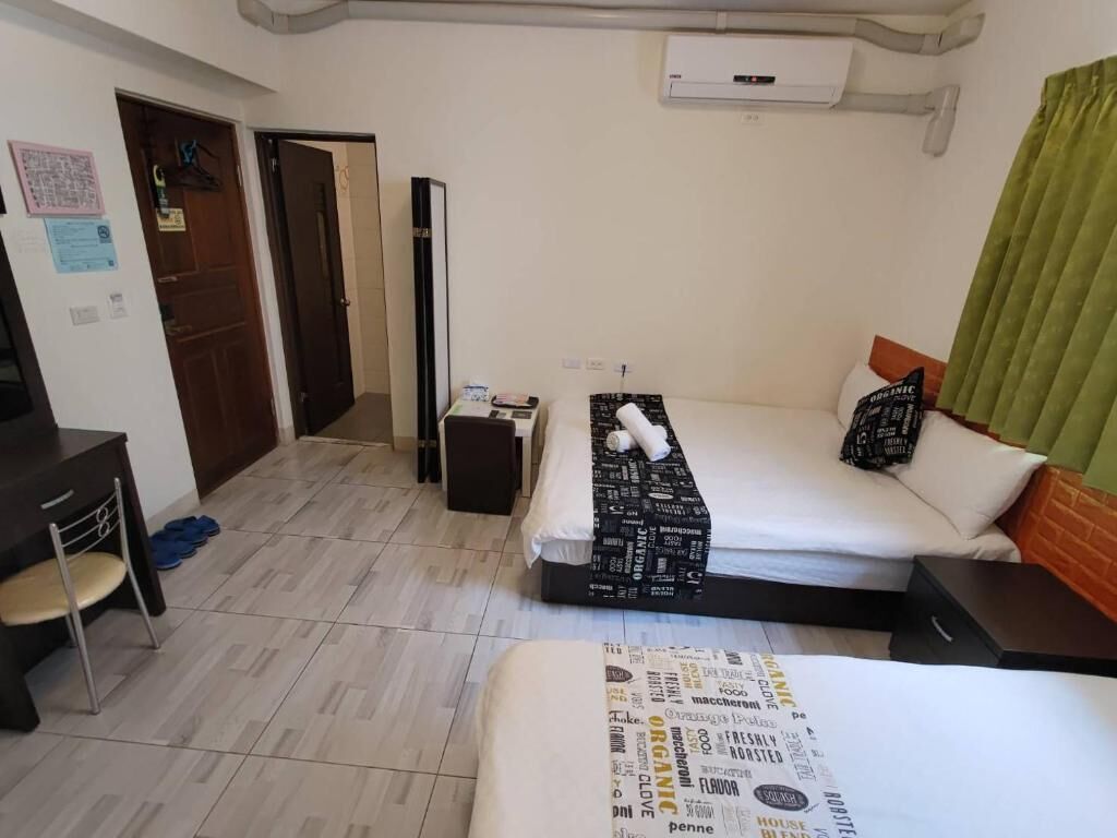 A hotel room with a bed, a desk, a chair, and a wardrobe.