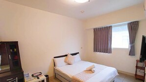 Une chambre à coucher avec un lit, un bureau, une chaise, un téléviseur et une fenêtre avec des rideaux.