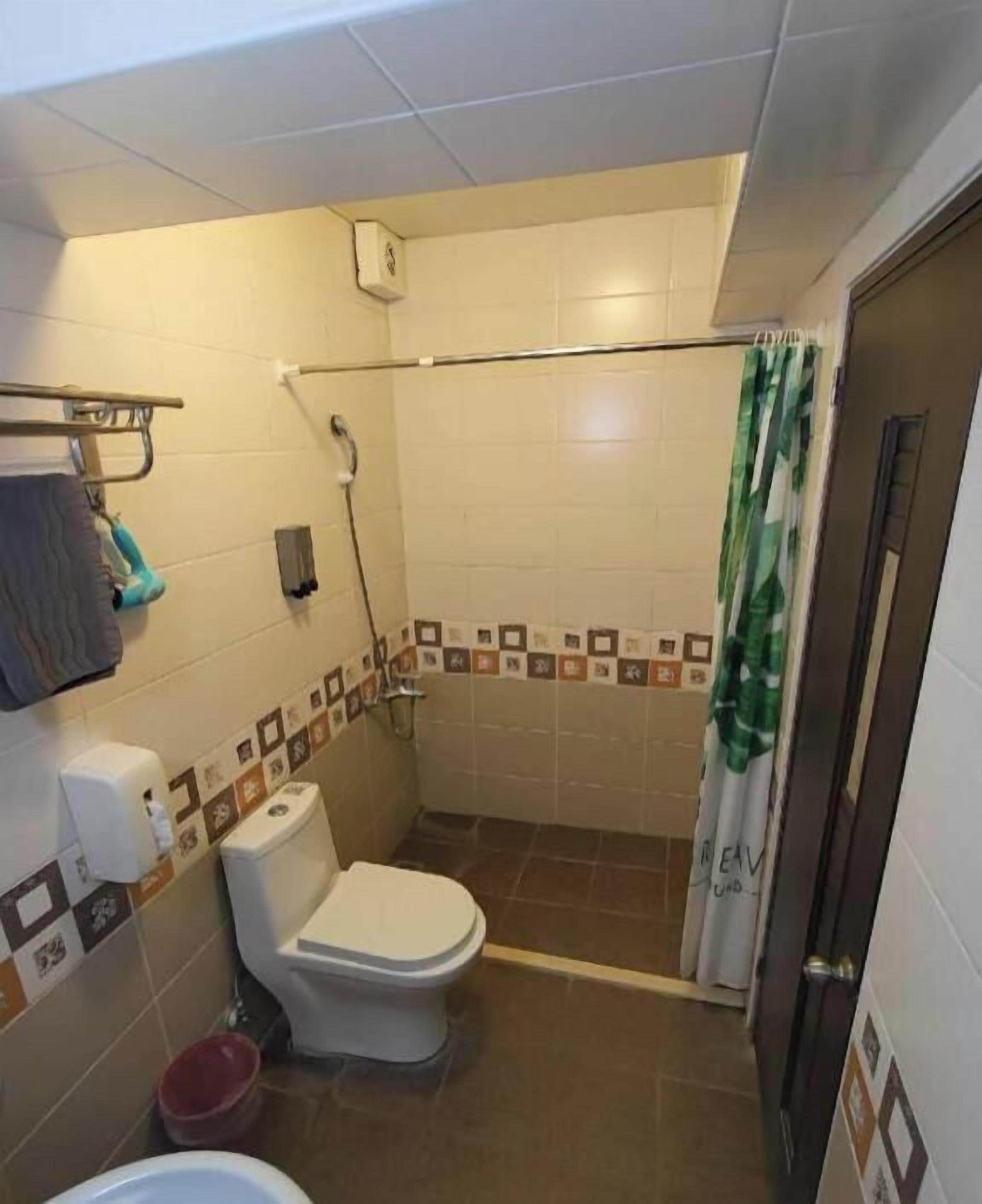 A small bathroom with a toilet, shower, and a towel rack.