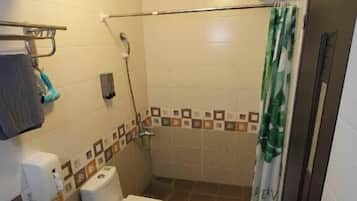 A small bathroom with a toilet, shower, and a towel rack.