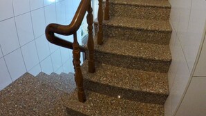 A staircase with granite steps and wooden handrails, leading to a landing with a small window. - Danke Hostel (Liuqiu)