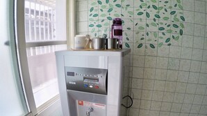 A water dispenser in a room with patterned tiles and a window. - Danke Hostel (Liuqiu)
