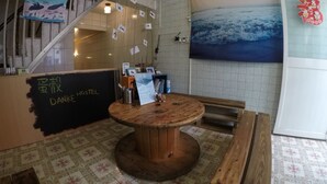 A hostel reception area with a wooden table, tiled floor, and a staircase. - Danke Hostel (Liuqiu)