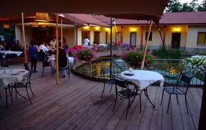 An outdoor dining area with tables and chairs, a pool, and a building in the background. - Agriturismo Cascina Madonnina (Pregnana Milanese)