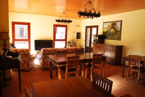 A dining area with a wooden table and chairs, a floral sofa, and a chandelier. - Agriturismo Cascina Madonnina (Pregnana Milanese)