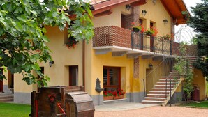 A yellow building with a balcony, a wooden barrel, and red flowers. - Agriturismo Cascina Madonnina (Pregnana Milanese)