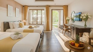 A hotel room with two beds, a desk, a TV, and a dining table with fruit. - Én Retreat Hoi An (Da Nang)