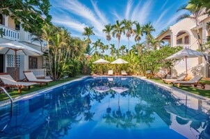 Una piscina rodeada de palmeras y sillas de descanso.