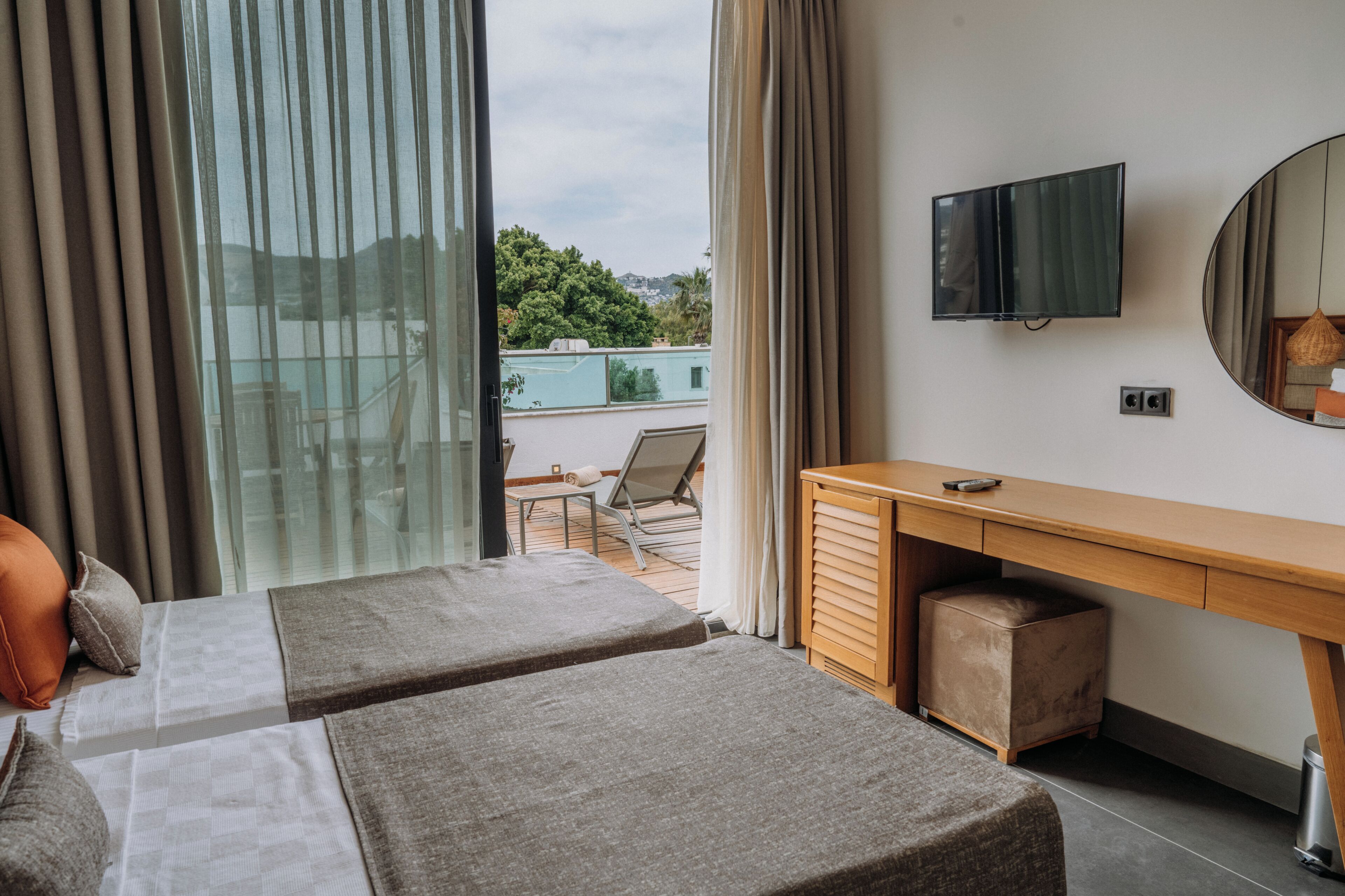 Ein Hotelzimmer mit zwei Betten, einem Schreibtisch, einem Fernseher und Blick ins Freie.
