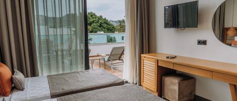 Ein Hotelzimmer mit zwei Betten, einem Schreibtisch, einem Fernseher und Blick ins Freie.