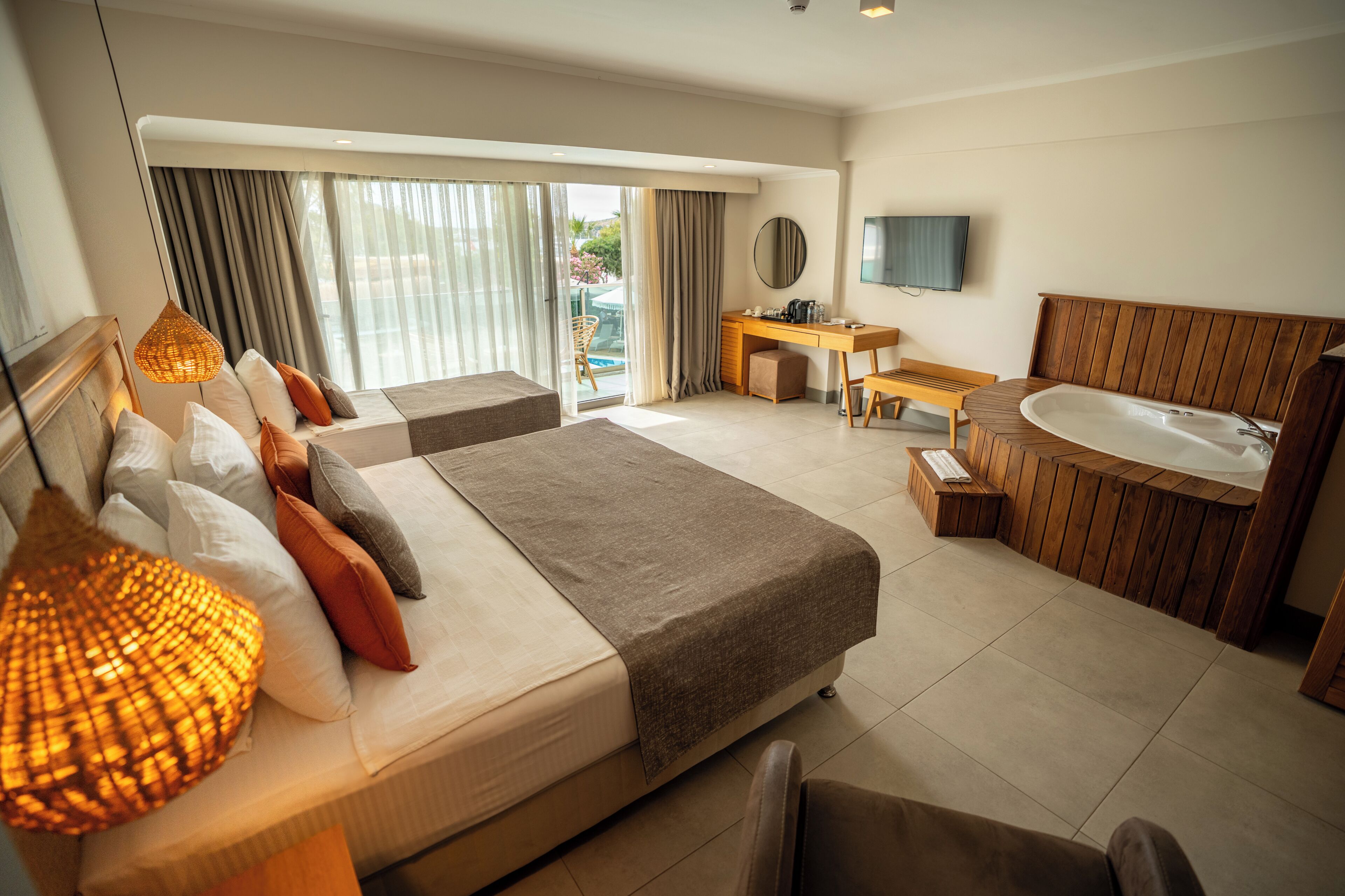 A modern hotel room with a large bed, a desk, a chair, a bathtub, and a TV.