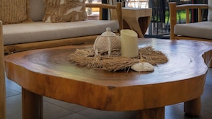 Un rincón acogedor con una mesa redonda de madera, un sofá con cojines y un amplio ventanal con vistas a zonas verdes.