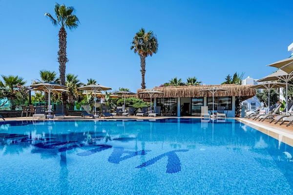 Una piscina al aire libre, sombrillas, sillones reclinables de piscina