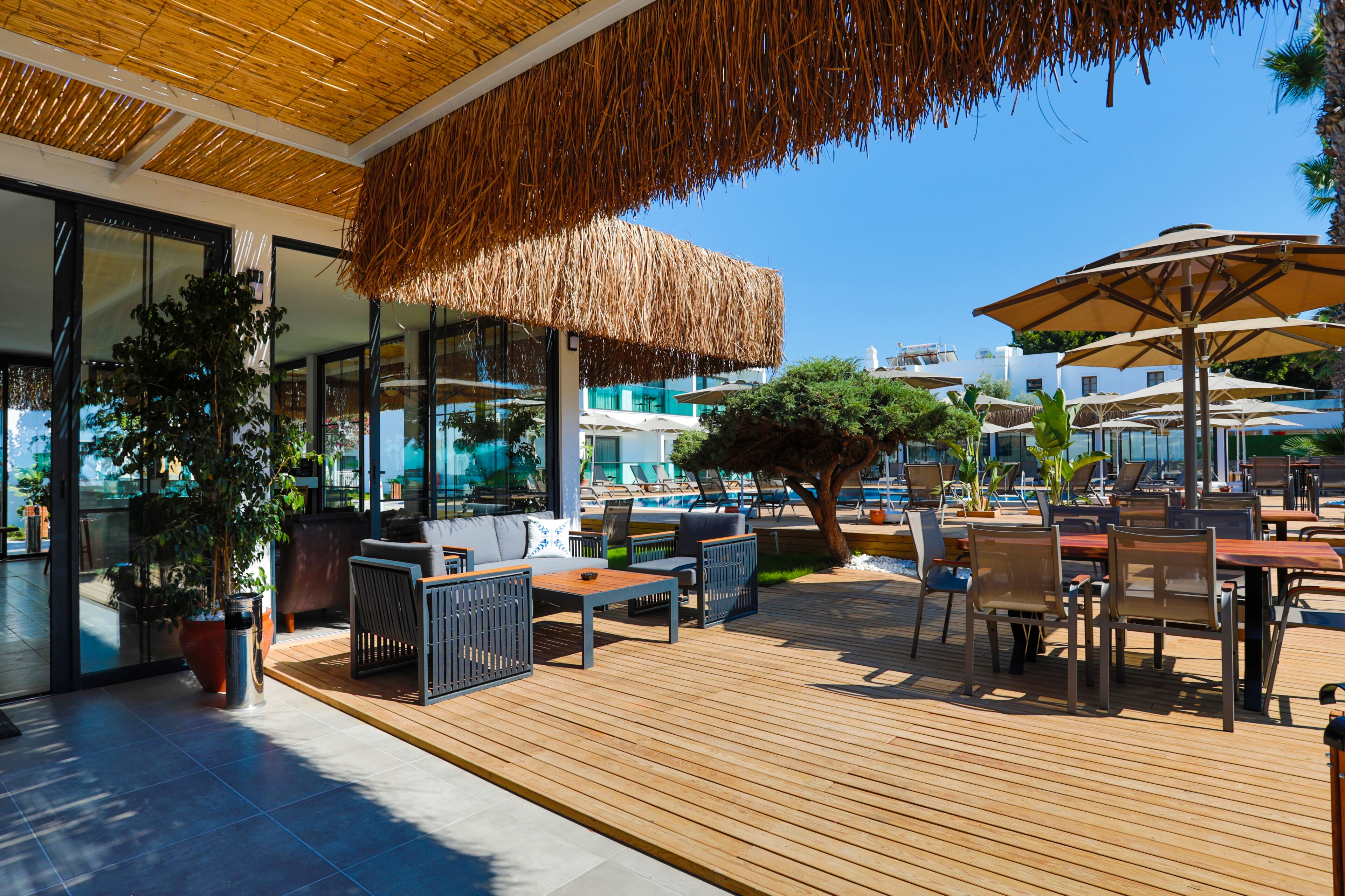 An outdoor patio with wooden flooring, seating arrangements, and umbrellas.