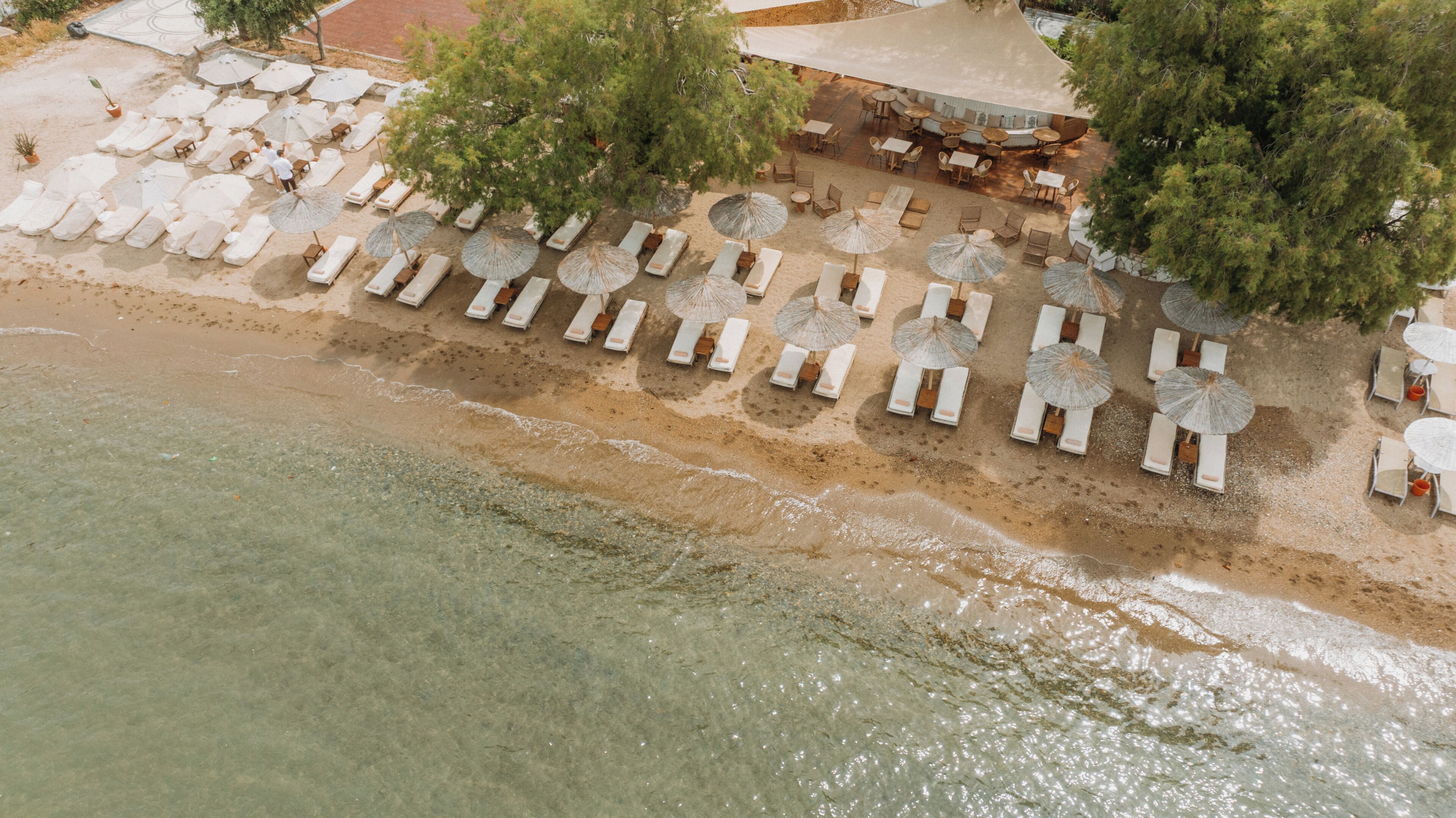 An aerial view of a beachside resort with sun loungers, umbrellas, and outdoor seating areas.