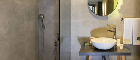 A modern bathroom with a glass-enclosed shower, a round mirror, and a wooden vanity with a sink.