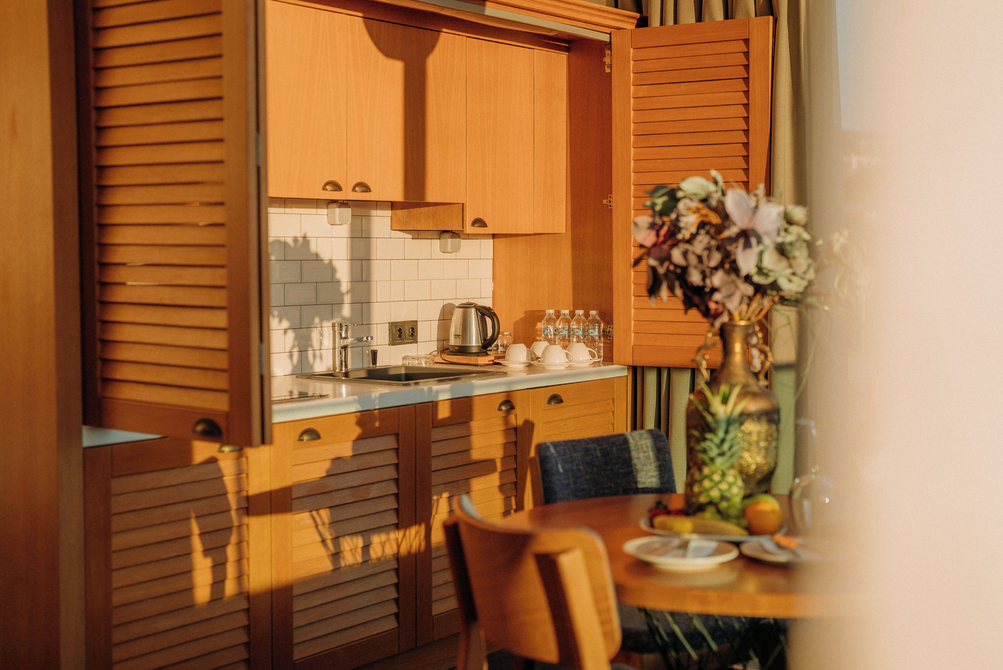 A kitchen with wooden cabinets, a sink, and a dining area with a table and chairs.
