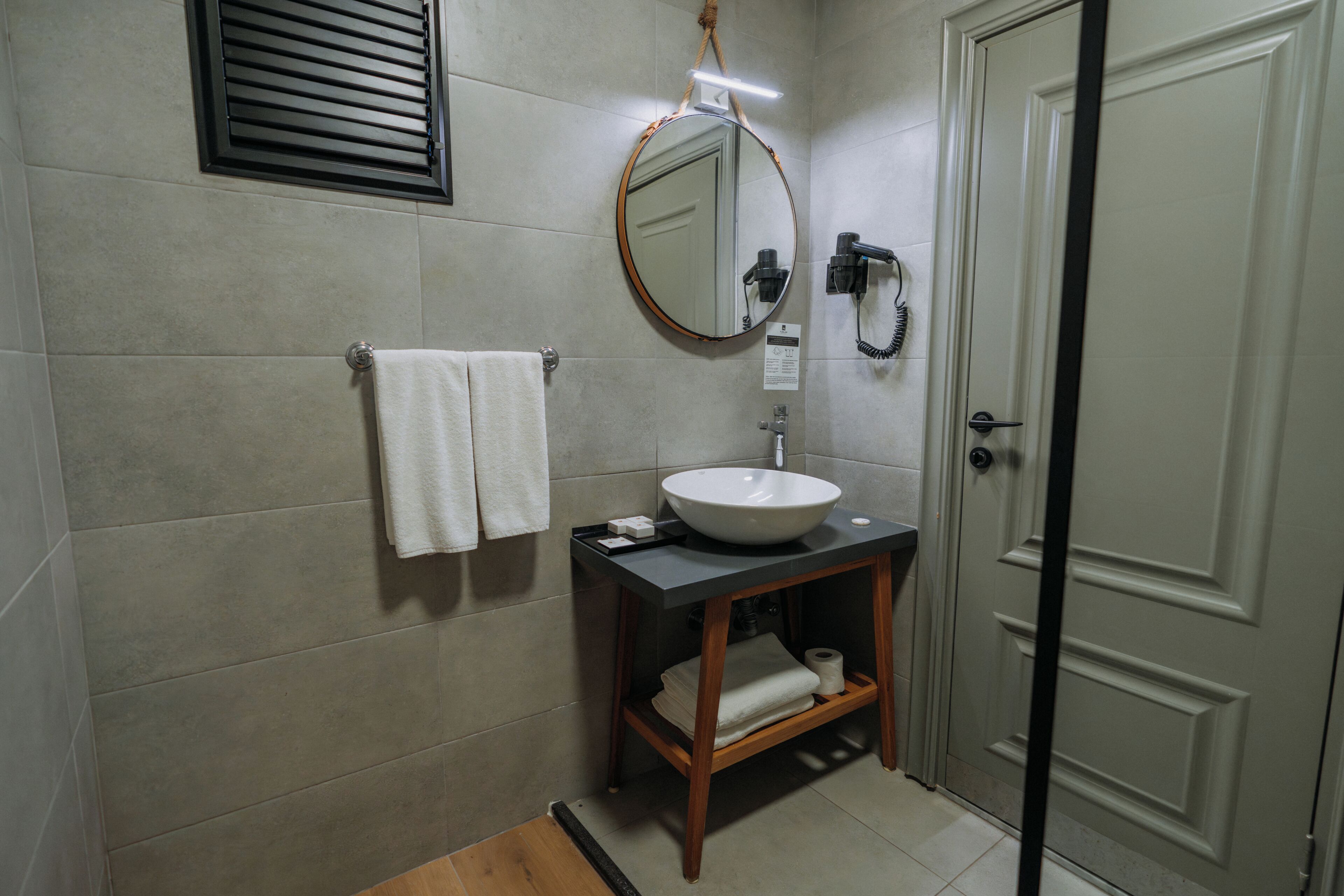 A bathroom with a sink, mirror, towel rack, and a door.
