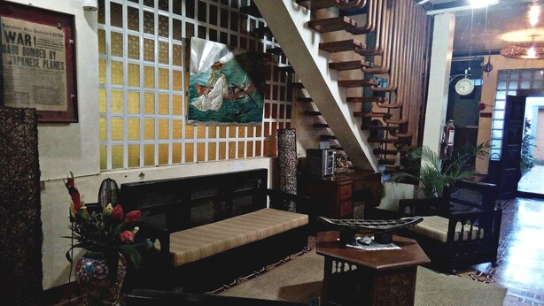 A traditional interior with a wooden staircase, a sofa, a coffee table, and a decorative vase.