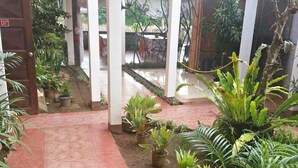 A covered outdoor area with potted plants, a tiled walkway, and a wooden door marked "EXIT".