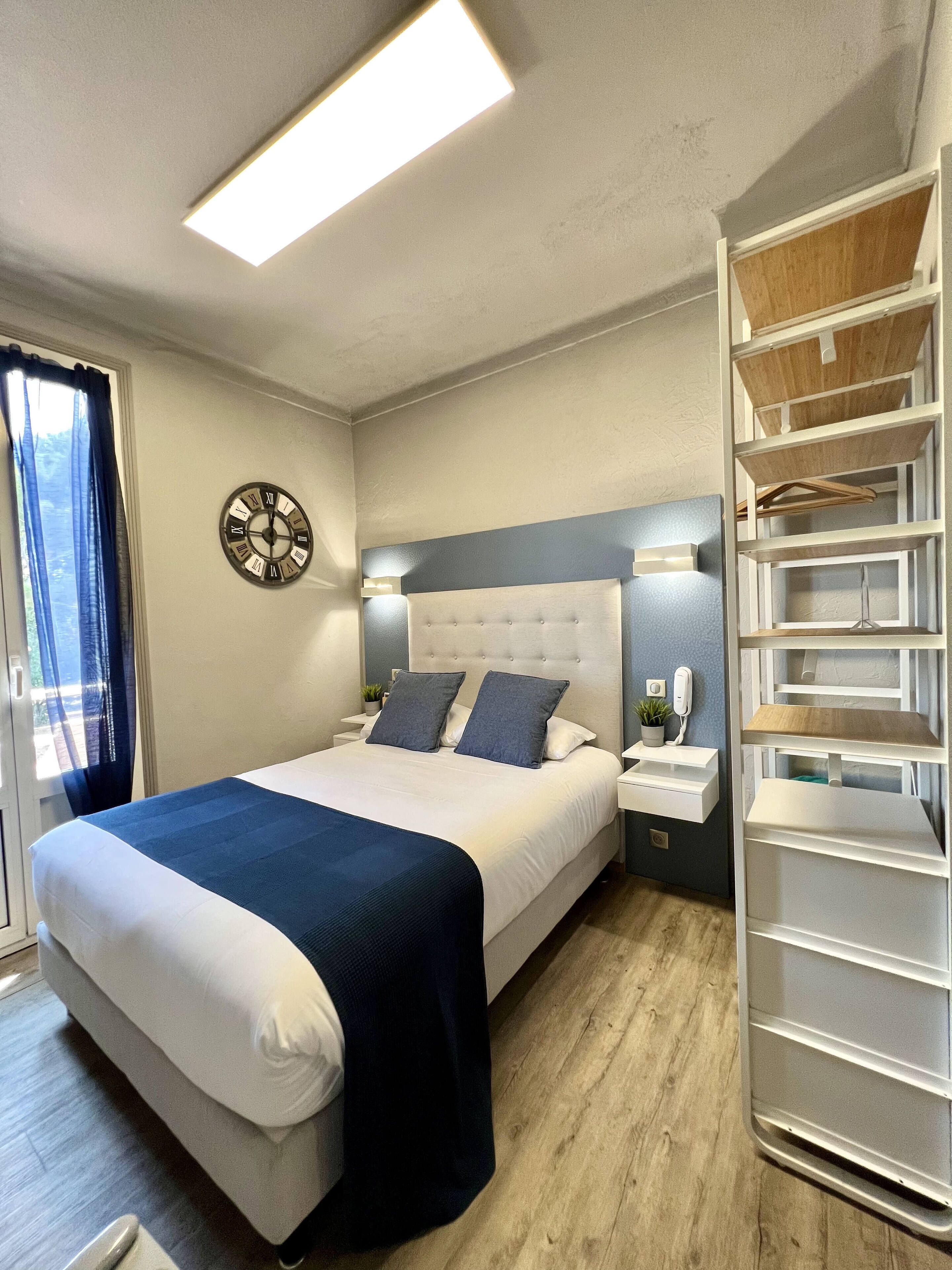 A neatly arranged bedroom with a bed, bedside tables, a clock, and a built-in wardrobe.