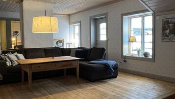 Un loft espacioso con techo alto, piso de madera, un sofá grande, una mesa de centro y una lámpara colgante.