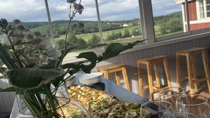 A dining table with a view of a green landscape through large windows. - Chinova Mötesgård (Jarvso)
