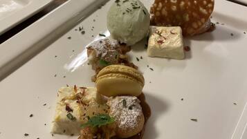 Une série d’assiettes carrées blanches, sur lesquelles sont présentés divers desserts, notamment des macarons, de la glace et d’autres gourmandises.
