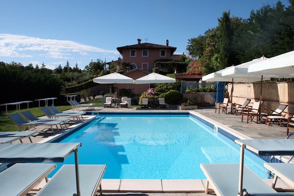 En säsongsöppen utomhuspool, parasoller och solstolar